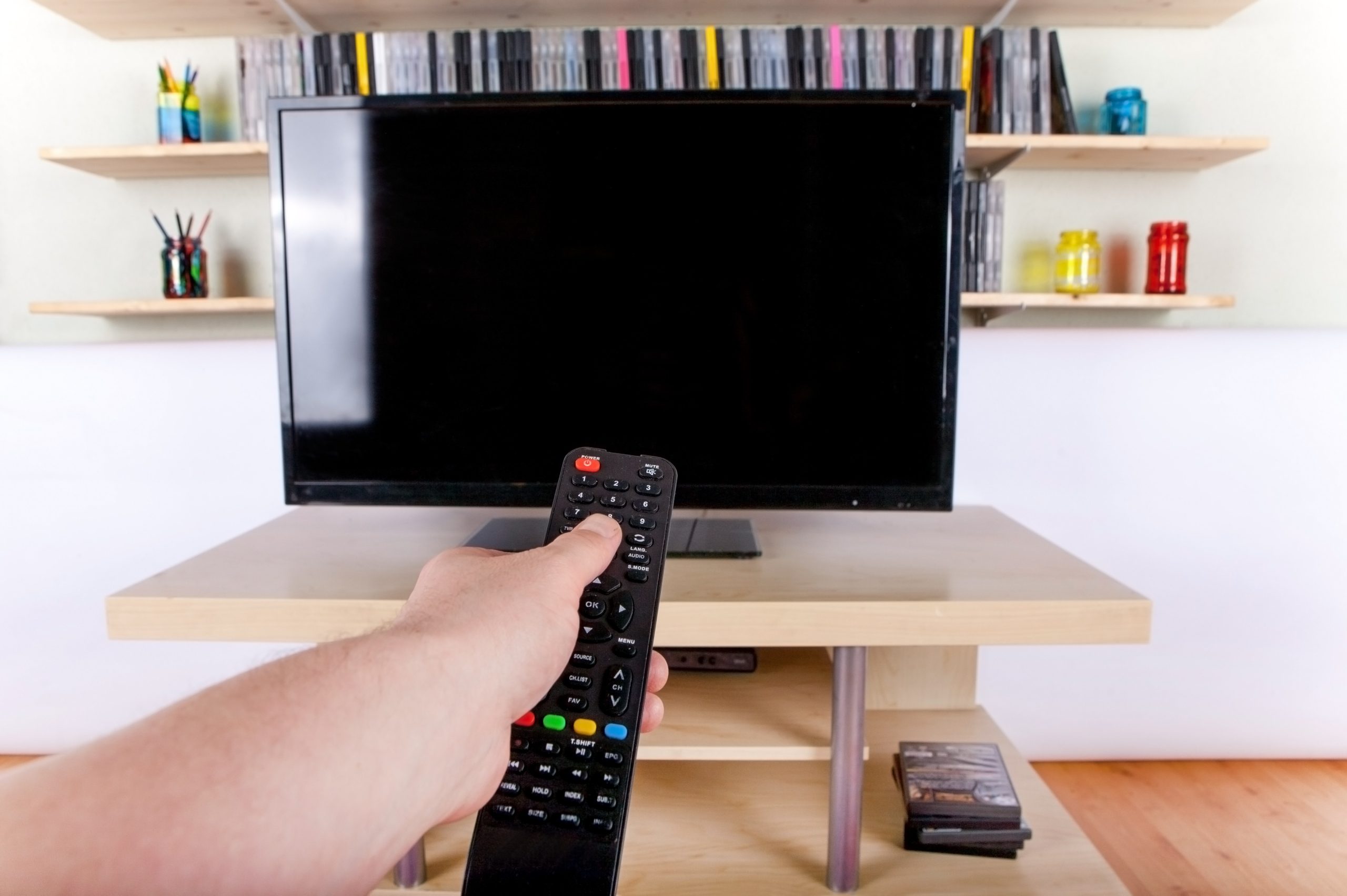 Hand using remote control in front of the TV