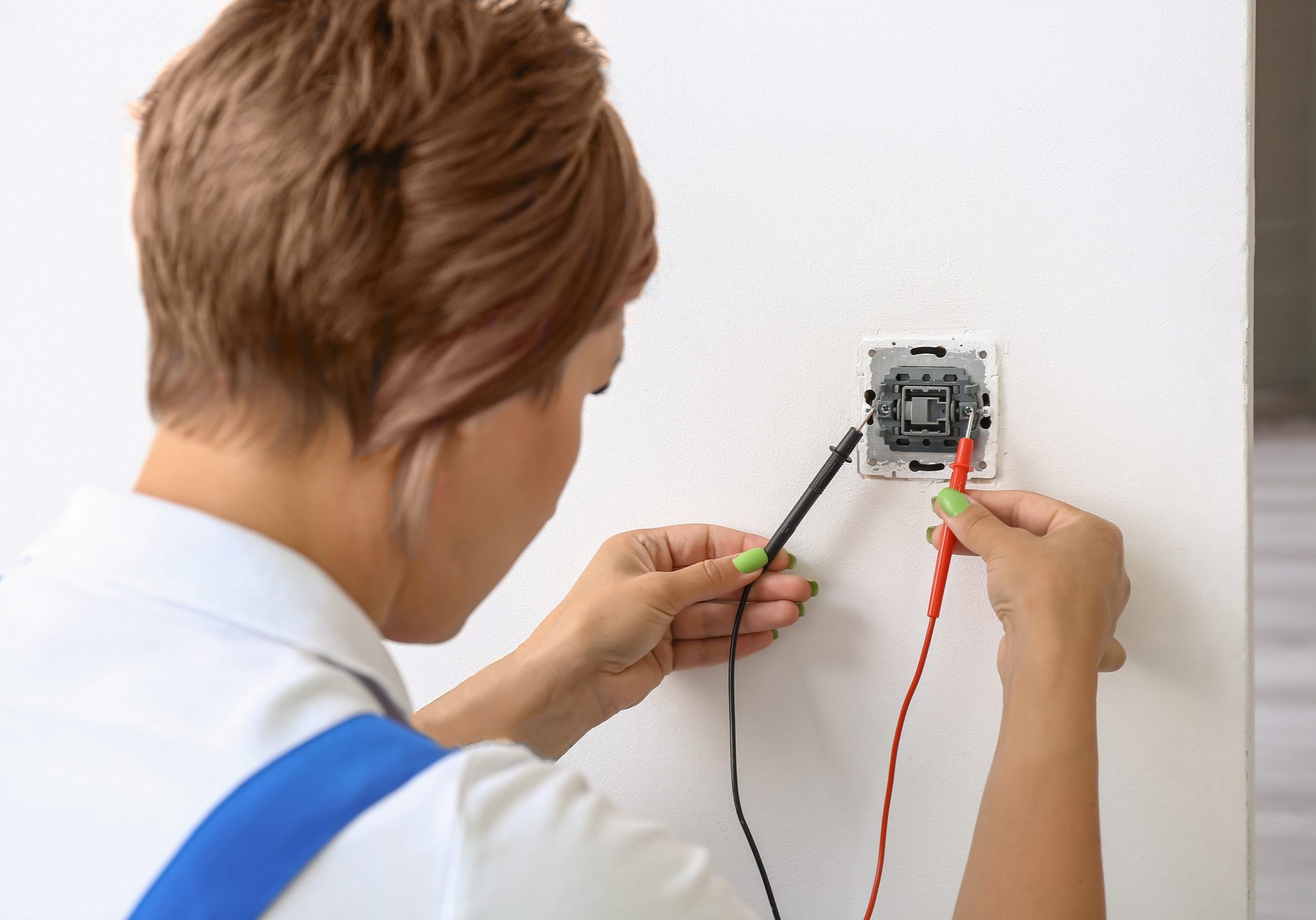 Female electrician measuring voltage of socket in room, closeup